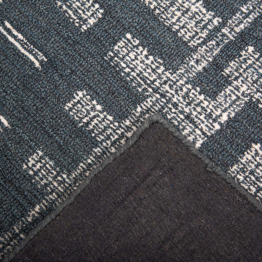 Close up of the hand-tufted Rizzy BX05BL area rug. Blue wool with ivory geometric pattern. Rug backing visible. Texture