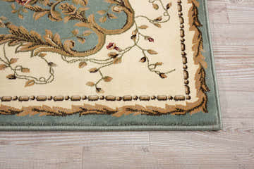 Close-up of Nourison Bordeaux Slate Blue Aubusson Rug showing floral pattern, blue border, and neutral background.