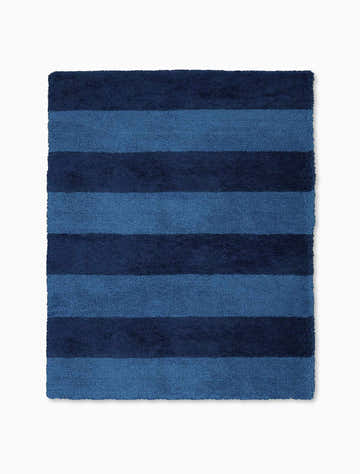 Close-up of the Calvin Klein Chicago Shag Blue rug. Features horizontal stripes in light and dark blue hues.