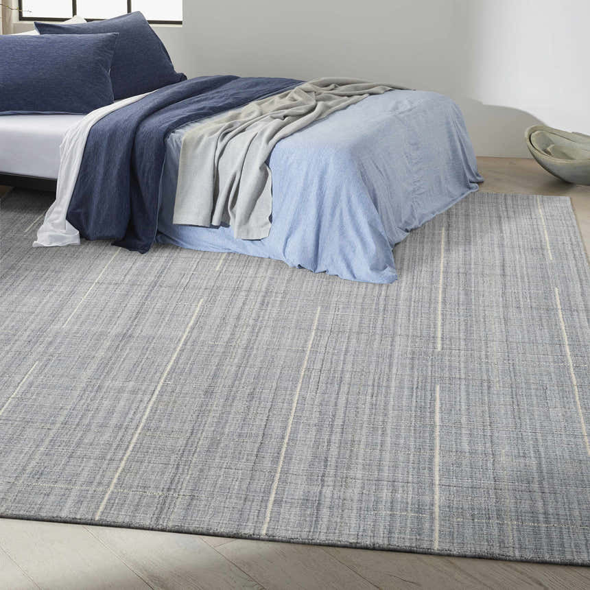 Bedroom scene with denim bedding and the Calvin Klein CK041 Architectura Denim rug, a farmhouse style rug with thin stripes.