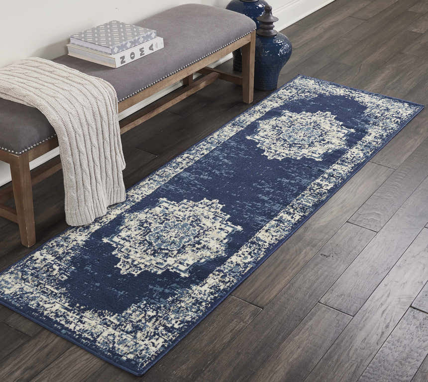 Entryway with a Nourison Grafix Navy Blue Vintage runner rug, gray bench, dark wood floors, and blue vases.