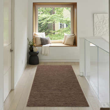 Hallway with window seat and Nourison Solutions Mocha Modern Washable Area Rug on light wood floor.