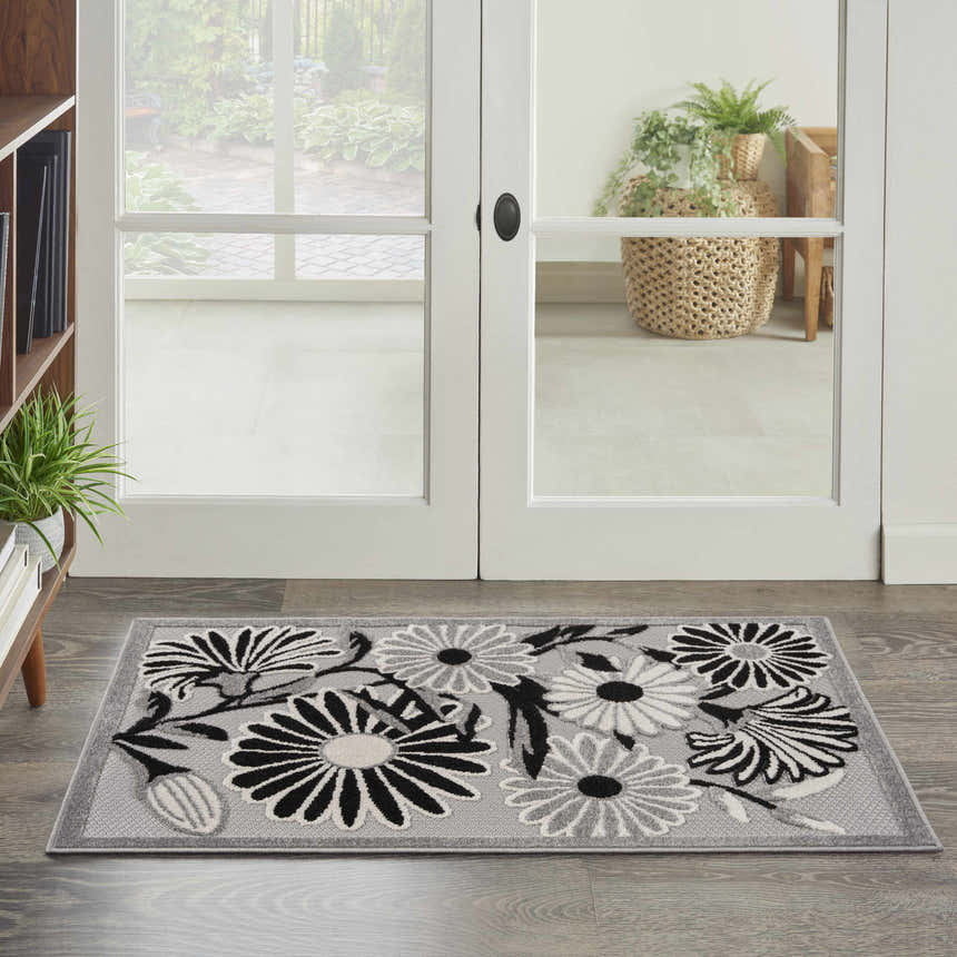 Entryway with Nourison Aloha Black White Outdoor Area Rug featuring a floral pattern on a gray background.