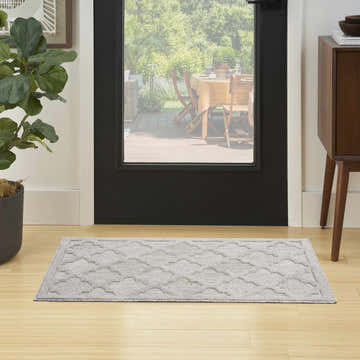 Entryway with Nourison Easy Care Silver Grey Modern Area Rug runner, wood floors, black door, and mid-century cabinet.