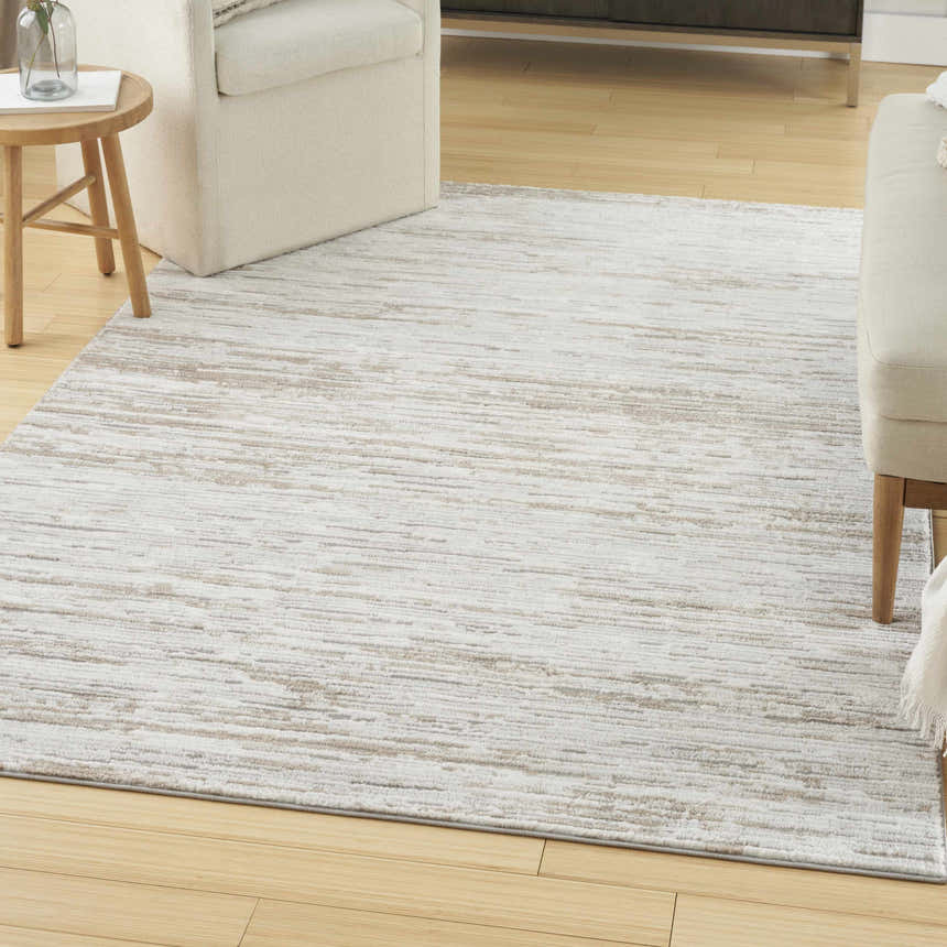 Living room scene with a Nourison Dew Silver Beige rug, cream furniture, and light wood floors.