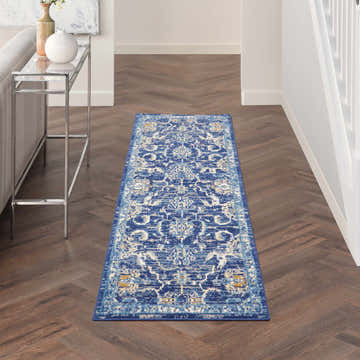 Hallway with Nourison Grafix Navy Vintage runner rug on dark wood floor. Console table and white stairs.