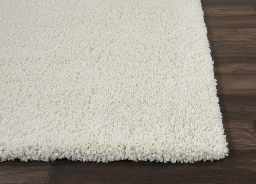 Close-up of the plush texture of the Nourison Malibu Shag Ivory rug on dark wood flooring.
