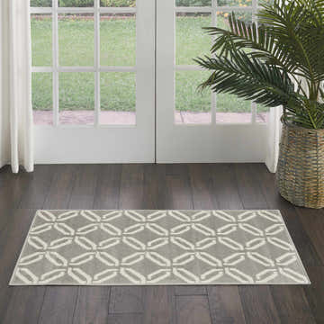 Entryway with Nourison Jubilant Grey rug, dark wood floors, white doors, and a potted palm. Contemporary style.