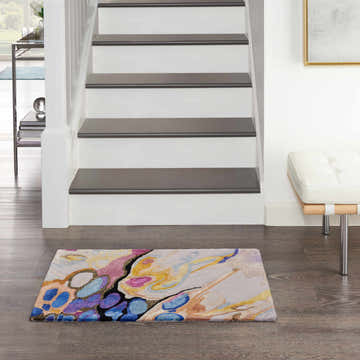 Entryway with Nourison Prismatic Grey Lilac Multicolor rug. Modern rug with blue, gold, and pink accents on wood floor near stairs.