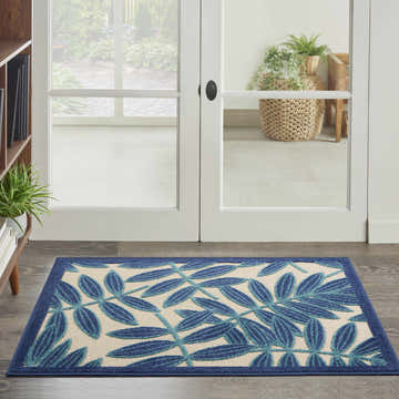 Entryway with a Nourison Aloha Navy Tropical Area Rug featuring a blue leaf pattern on a beige background.
