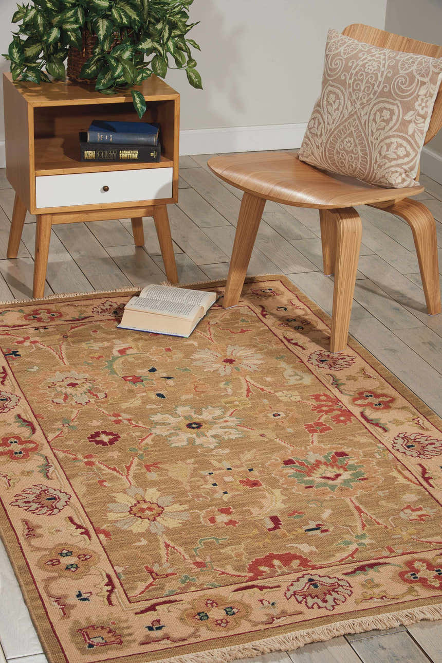 Living room scene with olive Nourison Nourmak vintage rug, wood chair and side table, and a book on the rug.