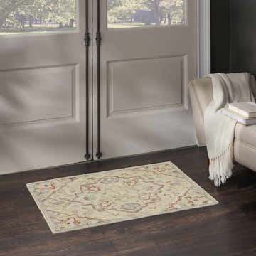 Entryway scene with a Nourison Maison Ivory Vintage Area Rug on dark wood floors near a white door and beige armchair.