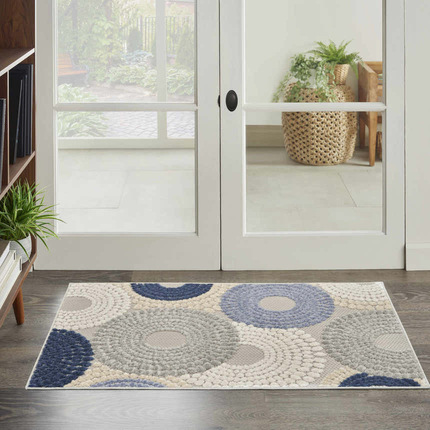 Entryway scene with a Nourison Aloha Blue Grey Modern Area Rug featuring a circular pattern in blue, gray, and white.
