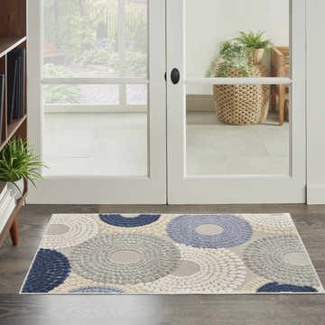 Entryway scene with a Nourison Aloha Blue Grey Modern Area Rug featuring a circular pattern in blue, gray, and white.