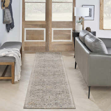 Entryway with a Nourison Lynx Ivory Taupe vintage rug, gray leather sofa, wooden bench, and rustic wood doors.