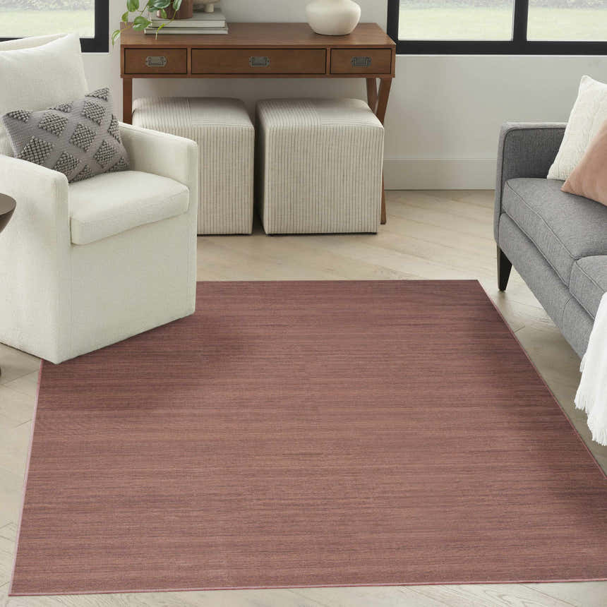 Living room scene with a Nourison Essentials Mocha rug, white chair, gray sofa, and wood desk.