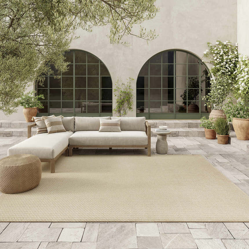 Cream patio scene with a light sofa and the Nourison Tulum Cream Outdoor Area Rug.