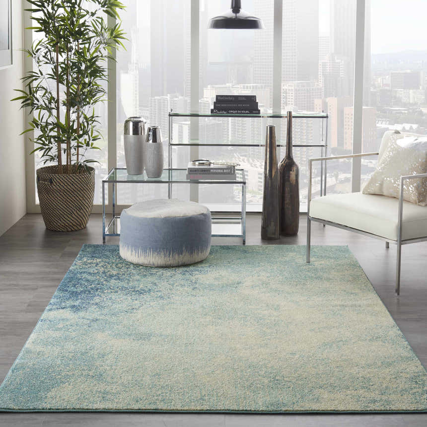 Modern living room with Nourison Passion Navy Light Blue rug, white chair, glass shelving, and city view.