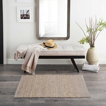 Entryway with bench, mirror, and Nourison Natural Jute Grey Farmhouse Indoor Area Rug on gray wood floor.