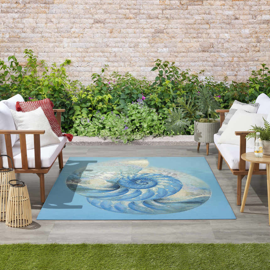 Coastal patio with white sofas and Nourison Color Splash Blue Ivory Area Rug featuring a nautilus shell design.
