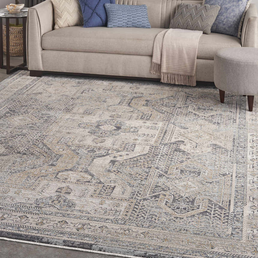 Living room scene with a beige sofa, blue pillows, and a Nourison Lynx Ivory Charcoal Vintage Area Rug.