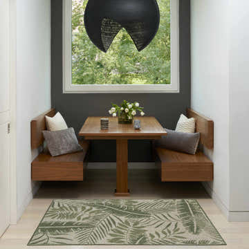 Breakfast nook with wood benches and Nourison Garden Oasis Ivory Green outdoor rug with palm leaf pattern.