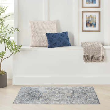 Bright entryway with Nourison Astra Grey Blue Vintage rug, pillows, throw, plant, and framed art.
