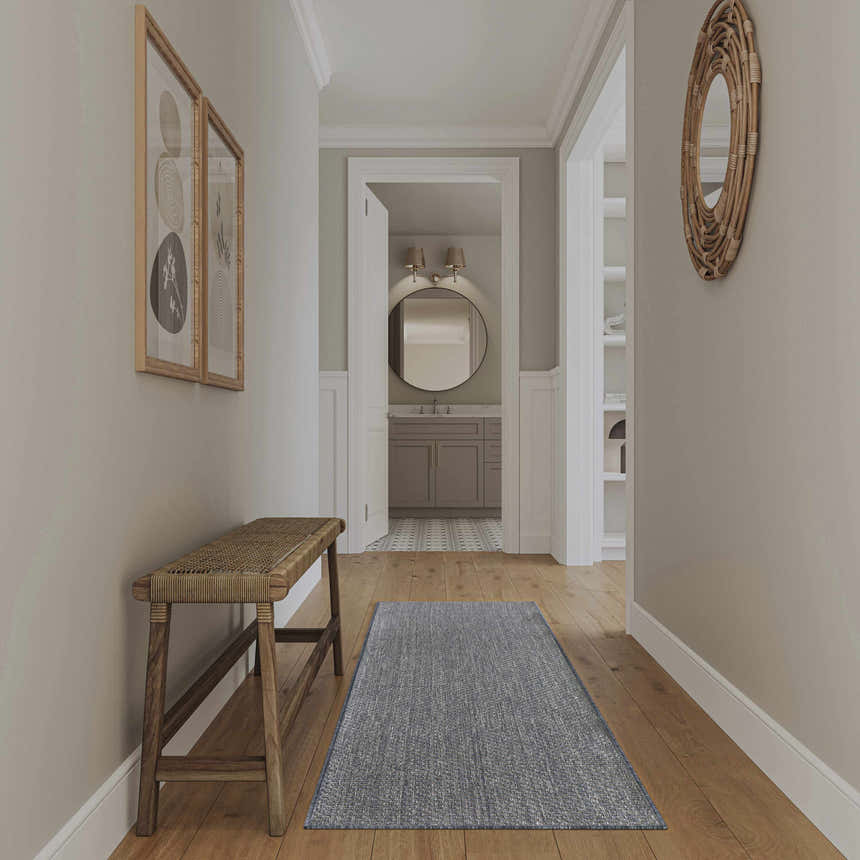 Hallway scene with a Nourison Tulum Denim Outdoor Area Rug runner and a wood bench.