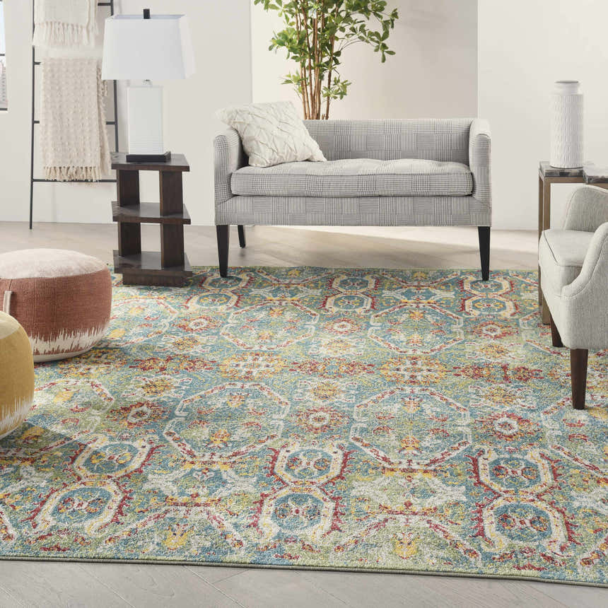 Living room scene with a Nourison Allur Turquoise Multicolor rug, grey sofa, chair, and wood accents.