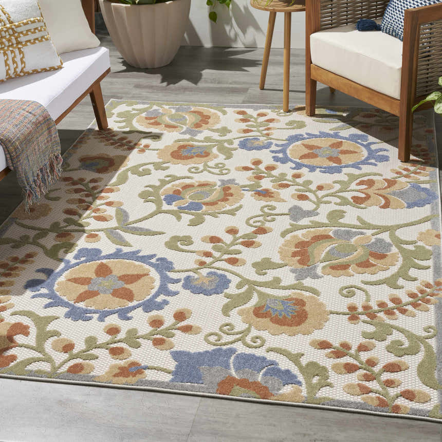 Outdoor patio scene with a Nourison Aloha Ivory Blue rug, wood furniture, and neutral cushions.