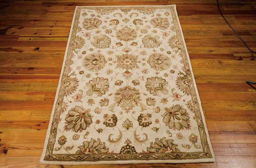 Close-up of Nourison Jaipur Ivory Persian rug showing chestnut floral pattern and handmade wool texture on wood floor.
