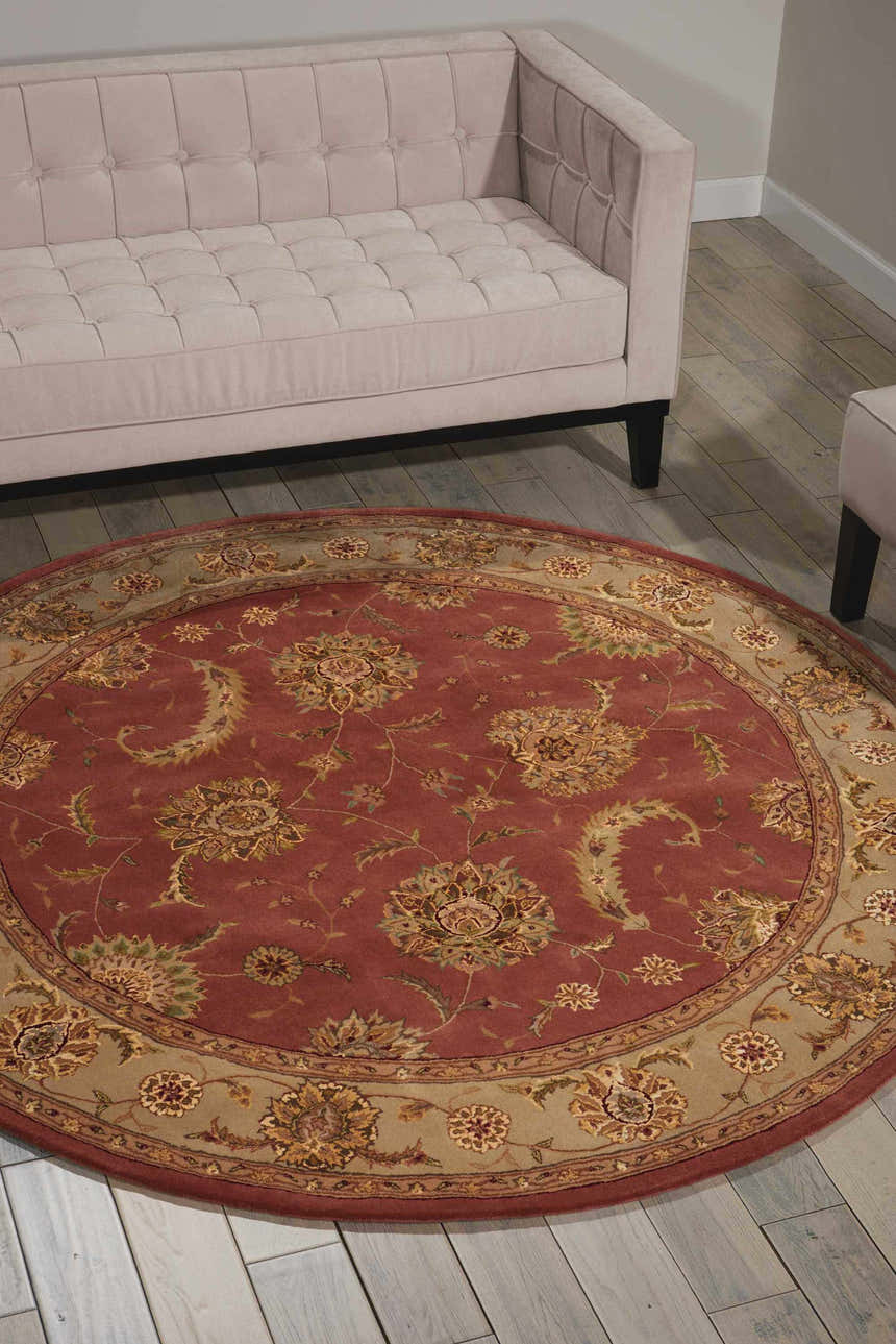 Living room scene with a round Nourison 2000 Rose Persian rug, pink sofa, and light wood floors.