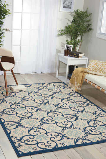 Living room scene with a Nourison Caribbean Ivory Navy rug, white sofa, and light wood floors.