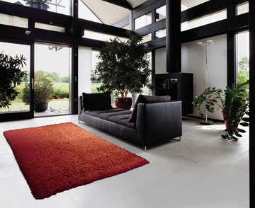 Modern living room with black sofa and Nourison Zen Red Shag Rug adding warmth to the light tile floor.