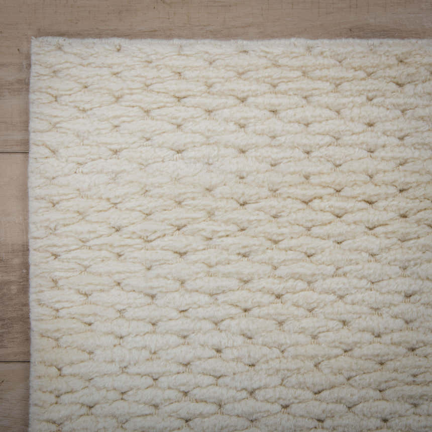 Close-up of the ivory Rizzy CLD707 area rug. Hand-loomed wool rug with a subtle, textured solid pattern. Corner