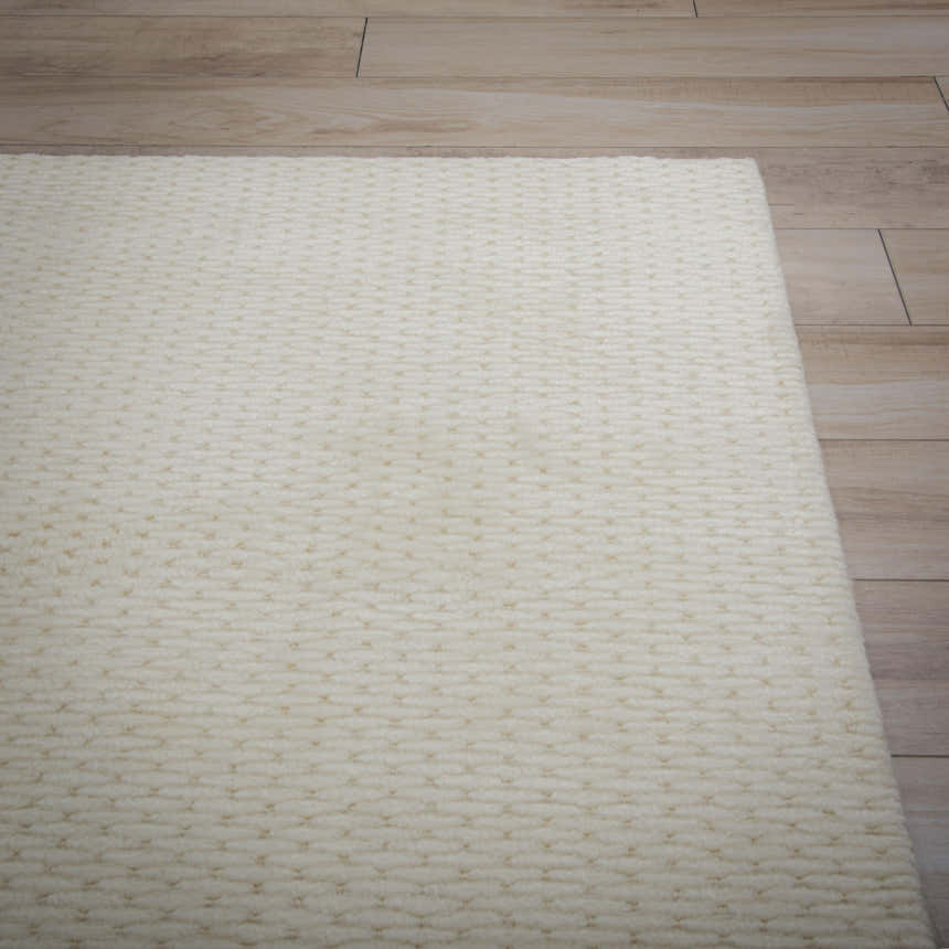 Close up of the ivory Rizzy CLD707 area rug showing its hand loomed texture and solid, tone on tone design. Corner