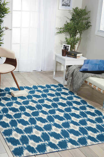 Bright living room scene with a Nourison Enhance Navy Indoor Area Rug on wood floors.