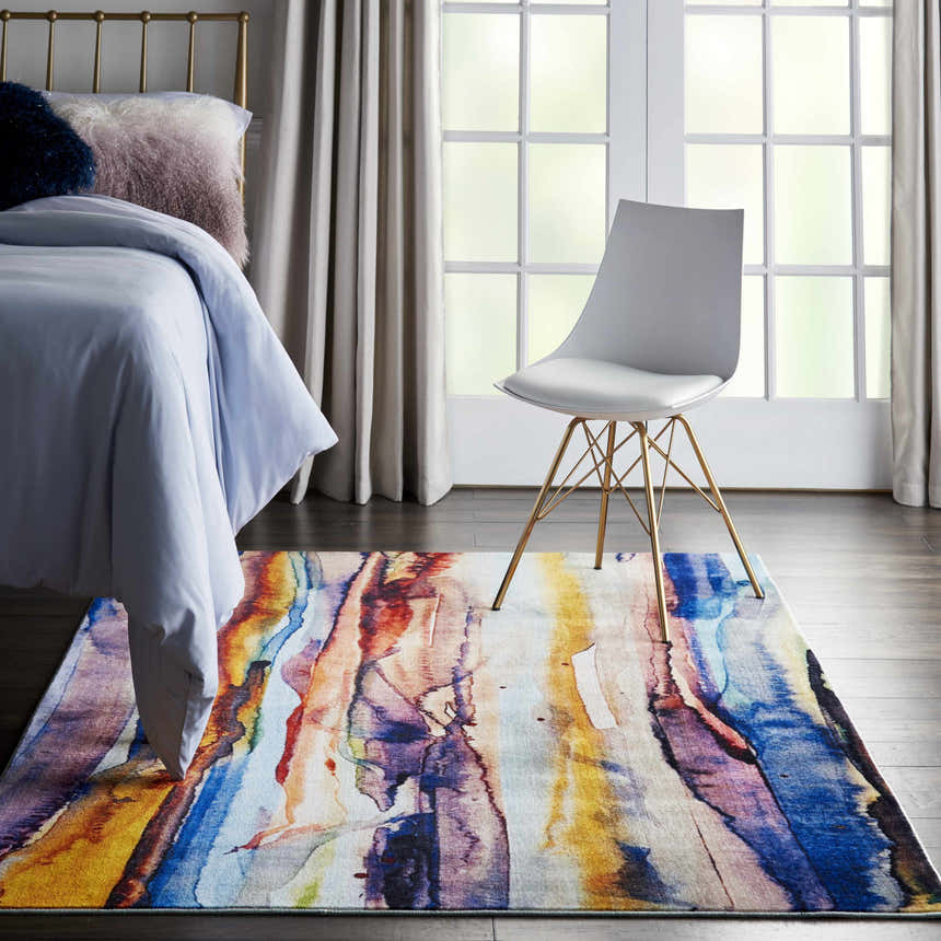 Bedroom scene with a Nourison Le Reve Multicolor rug, gold bed frame, and white chair near a window.