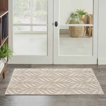 Entryway scene with a Nourison Aloha Ivory Grey Tropical Area Rug on dark wood floors near white doors.