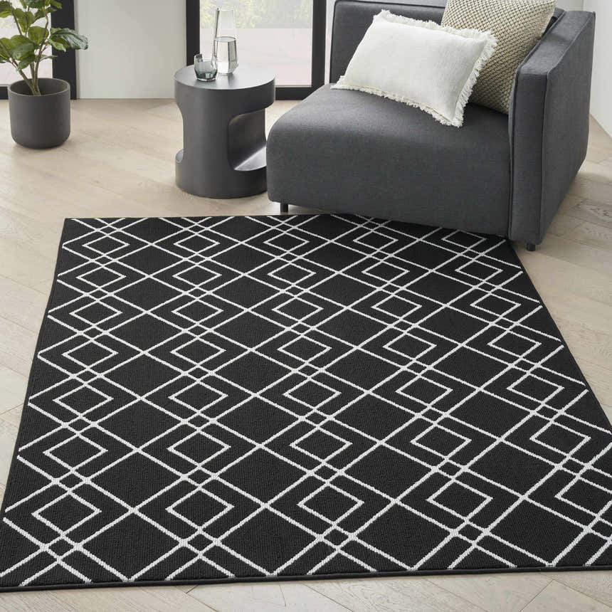Modern living room with gray chair and Nourison Modern Lines Black rug featuring a white geometric pattern.