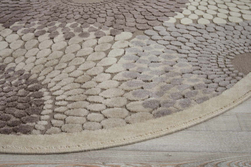 Close up of the round Nourison Graphic Illusions rug in gray, featuring a textured pebble pattern.