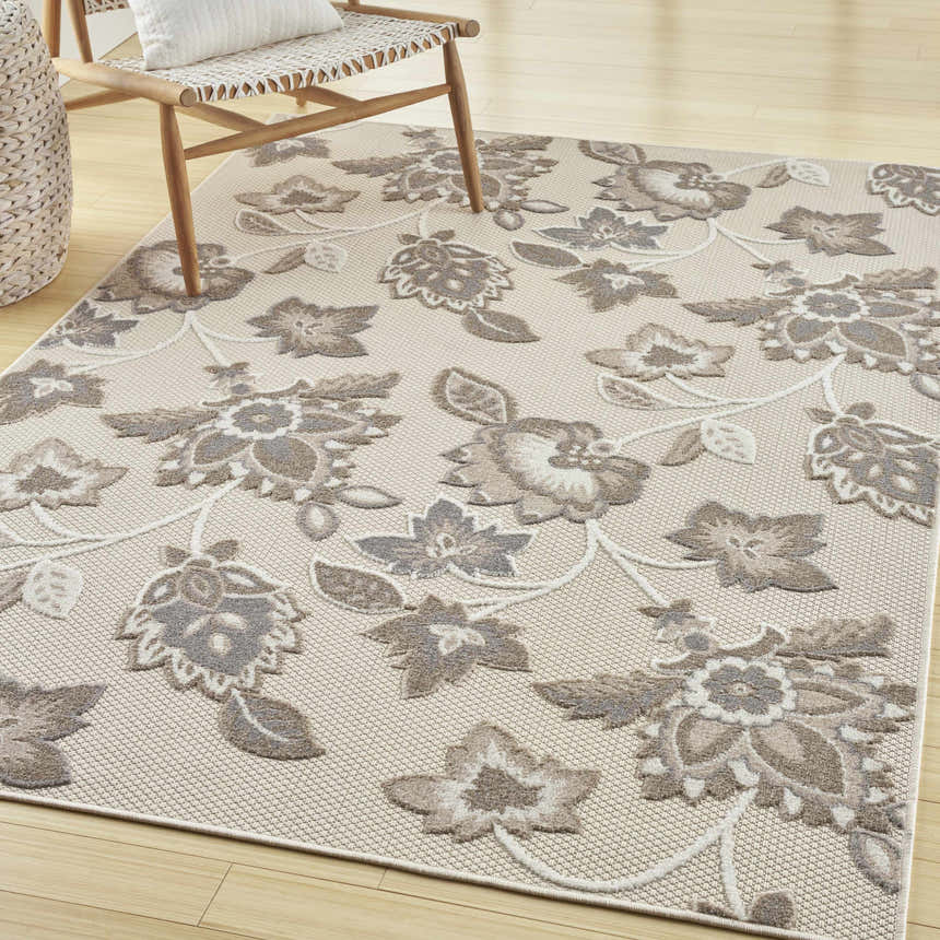 Farmhouse style room with a Nourison Aloha Beige rug, wood floors, and woven chair.