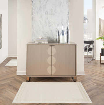 Hallway scene with a Nourison Essentials Ivory Gold rug, wood floors, and a modern cabinet.