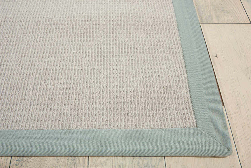 Close-up of the Nourison Sisal Soft Stone rug. Sandstone woven texture with light blue border. Farmhouse style.