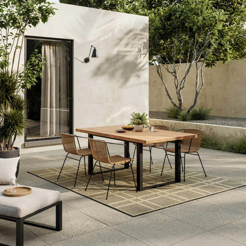 Outdoor patio scene with wood table, chairs, and Nourison Horizon Charcoal Modern Area Rug in taupe.