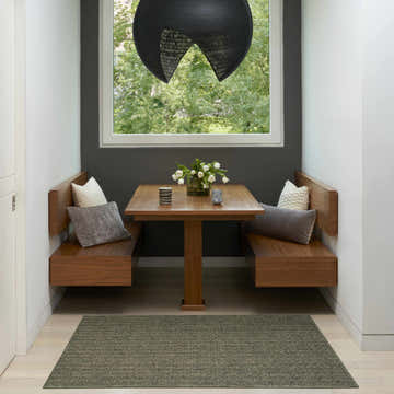 Dining nook with wood furniture and olive Nourison Tulum Outdoor Area Rug on light wood floor.