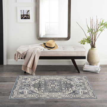 Entryway with bench, mirror, and Nourison Quarry Navy Ivory Vintage Area Rug on gray wood floor.