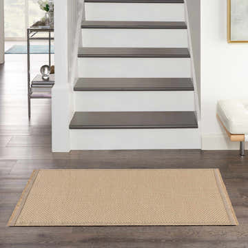 Entryway scene with a Nourison Jute Natural runner rug in brick red on dark wood floors, stairs, and modern decor.