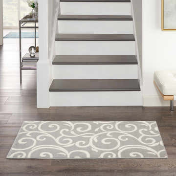 Entryway with Nourison Grafix Grey Contemporary Indoor Area Rug runner, hardwood floors, and staircase.