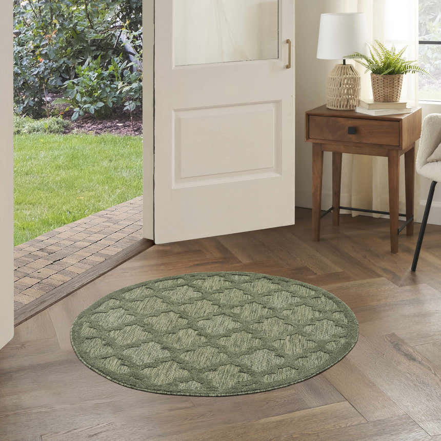 Entryway with a round Nourison Easy Care Green Modern Area Rug on wood floors near an open door.